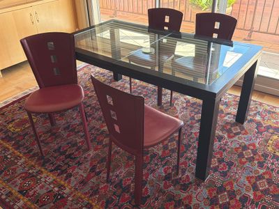 a glass table with four chairs and a rug on the floor
