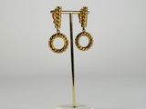 a pair of gold earrings on a stand with a white marble base