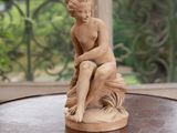 a statue of a boy sitting on top of a wooden table