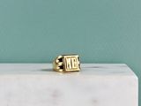 La bague en or repose sur un bloc de marbre blanc