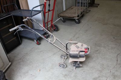 une petite tondeuse à gazon rangée dans un garage