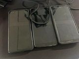 three cell phones sitting on a table with a bag