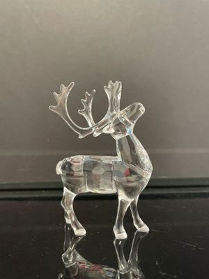 figurine de renne en verre transparent posée sur une surface noire
