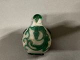 a green and white glass bottle with a dragon on it