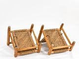 pair of wooden chairs with woven seats on them against a white background