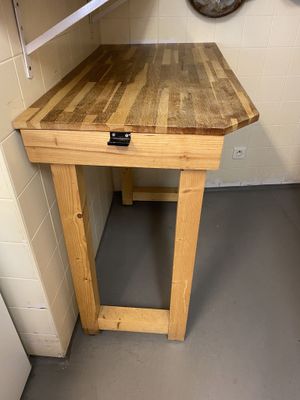 a small table with a wooden top in the corner of a room