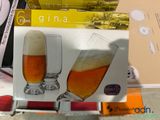 two glasses of beer sitting on a table next to each other
