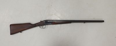 un fusil posé sur un mur blanc