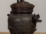 an antique bronze urn with a bird on top of it on a table