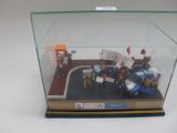 une vitrine dans laquelle sont exposées des figurines représentant des personnes et une voiture