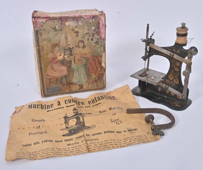 une vieille machine à coudre à côté d'une boîte sur laquelle figure une image