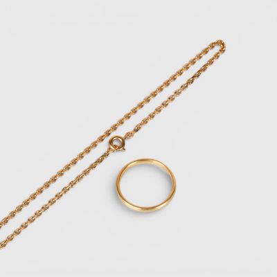 une bague et une chaîne en or sur fond blanc