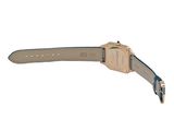 the back of a watch with a gold case and a blue strap
