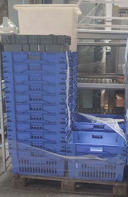 un homme debout à côté d'une pile de caisses bleues