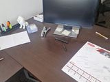 a desk with a monitor, keyboard, phone, and other office supplies on it