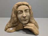 sculpture représentant le visage d'une femme aux longs cheveux, posée sur une table