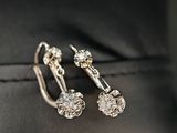 une paire de boucles d'oreilles en diamant posée sur une surface en cuir noir