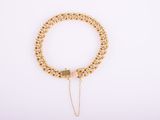 a gold chain bracelet with a heart charm on a white background