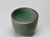a small green bowl sitting on a white surface