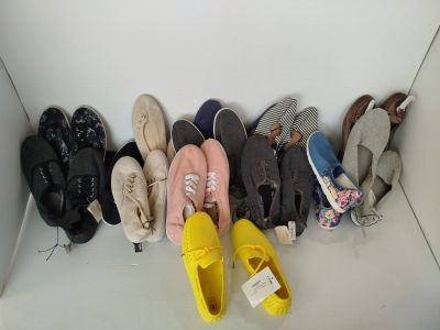 Plusieurs paires de chaussures sont alignées en rangée sur le sol
