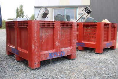 two red crates sitting next to each other on the gravel
