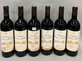 six bottles of wine are lined up in a row on a table