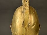 an antique helmet on a stand against a black background