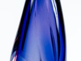 un vase en verre bleu avec un couvercle doré, posé sur une surface blanche