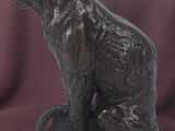 bronze statue of a cat sitting on a base on a red cloth