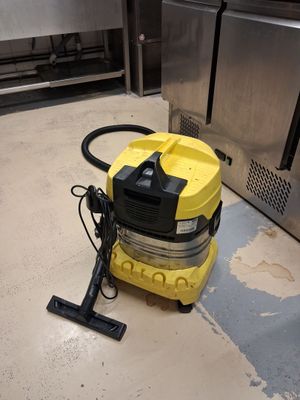 un aspirateur jaune posé par terre dans la cuisine