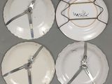 quatre assiettes blanches ornées de rubans argentés, posées sur une table