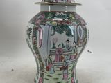 a vase with a lid that has a picture of a woman in a garden