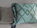 two pillows with fringes on them sitting on a white surface