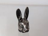 a close up of a small silver rabbit head on a table