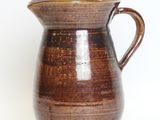 a brown pitcher with a handle on a white background