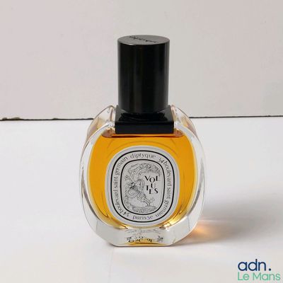 une image représentant un flacon de parfum posé sur une surface blanche