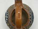 a small vase with a handle on a white surface