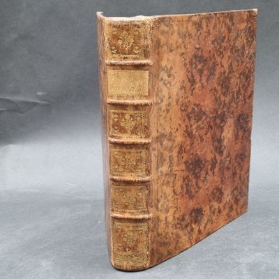 an old book sitting on top of a table covered in books