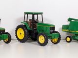 three toy tractors sitting next to each other on a white surface