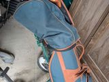 un sac de voyage bleu et orange posé par terre à côté d'une paire de chaussures