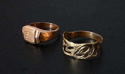 two gold rings with a signet on them sitting on a black surface
