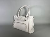 the white purse is sitting on the table on a gray surface