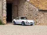 une petite voiture blanche garée devant un bâtiment en pierre