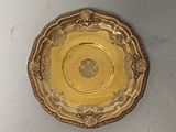a gold plate on a white table with a white wall behind it