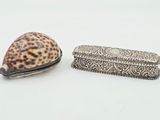 un coquillage et une boîte en argent posés sur une surface blanche