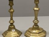 une paire de bougeoirs anciens en laiton posés sur une table blanche