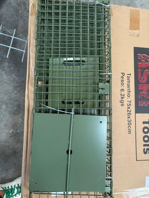 a bird cage with a bird inside of it on the ground