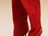 une paire de bottes rouges à talons hauts posées sur une surface blanche