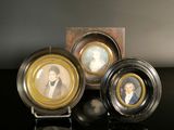 three miniature portraits of people are displayed on a black surface
