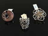 three silver and gold rings on a black surface with a tag